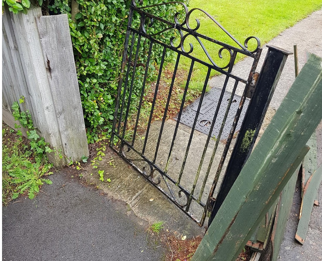 damaged gate with rust and the post coming out of the ground