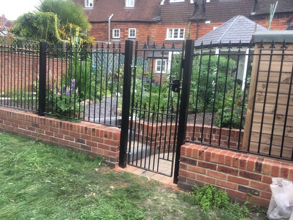 Spear top metal fence panels fitted to the top of a garden wall at the rear of a residential property